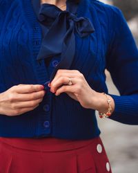 Modemarken. Close-up von einer Frau, die ihren Cardigan zuknöpft